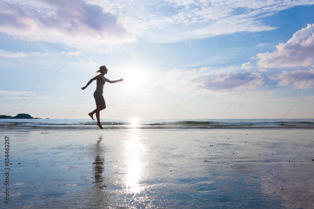 Woman is jumping to sky on beautiful sunset sea beach with wet sand. Free power mind or meditation and zen concept. Woman is jumping to sky on beautiful sunset sea beach with wet sand. Free power mind or meditation and zen concept.