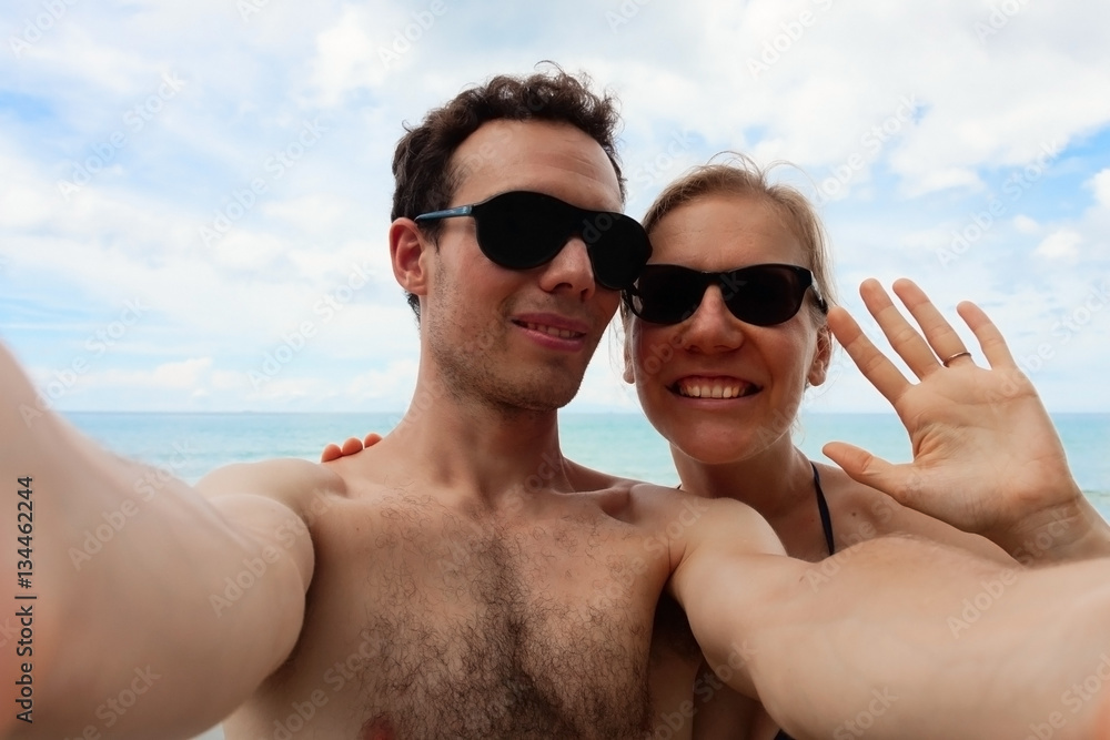 Young happy couple is making selfie. Close up portraits of man and woman in vacation on sunny sea beach. Young happy couple is making selfie. Close up portraits of man and woman in vacation on sunny sea beach.