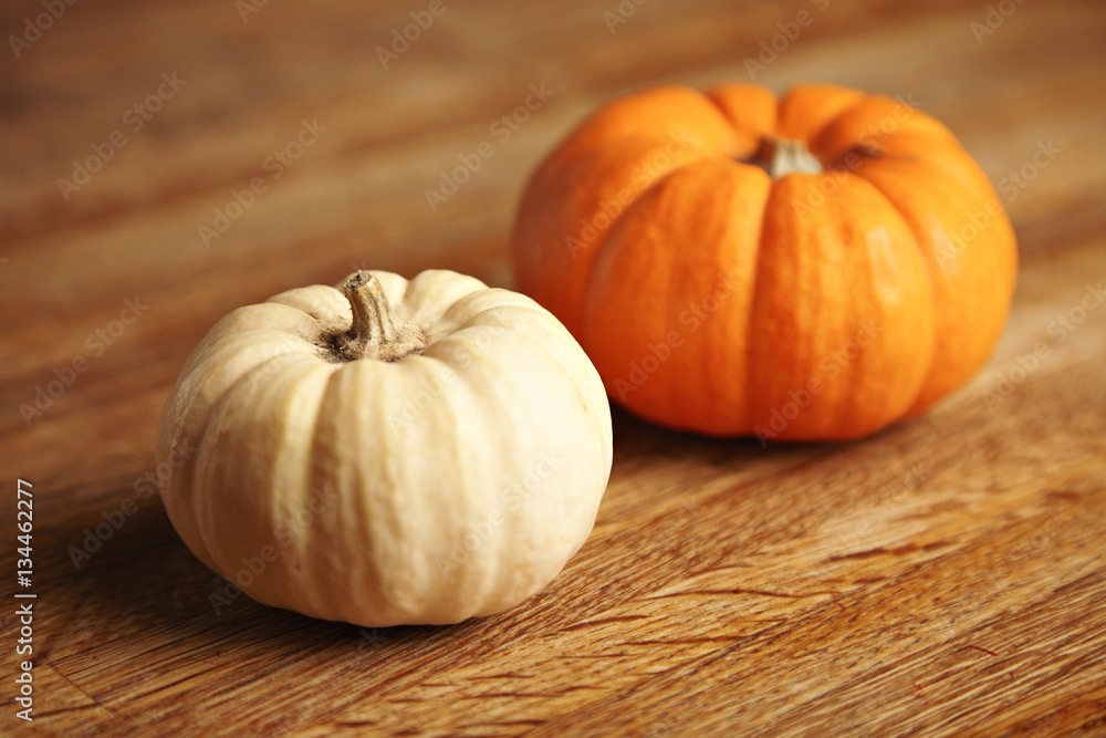 Two different pumpkins, orange and white, isolated on artisan wooden rustic table Two different pumpkins, orange and white, isolated on artisan wooden rustic table