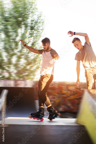 Young people rollerblading. Two guys outdoor. Friends in skate park.