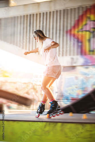 Girl on rollerblades. Young woman on blurred background. Ride with grace.