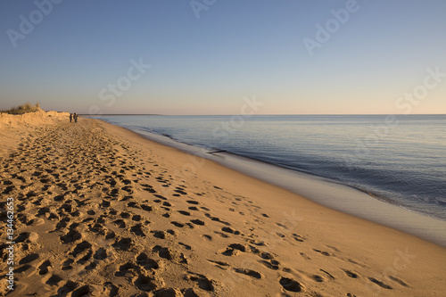 view on a beach at sunset with golden sand an quiet sea