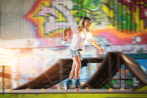 Young woman rolllerblading. Girl near graffiti. The graceful sportswoman.