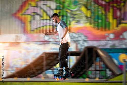 Young male rollerblading. Person near graffiti. Speed and precision of moves.
