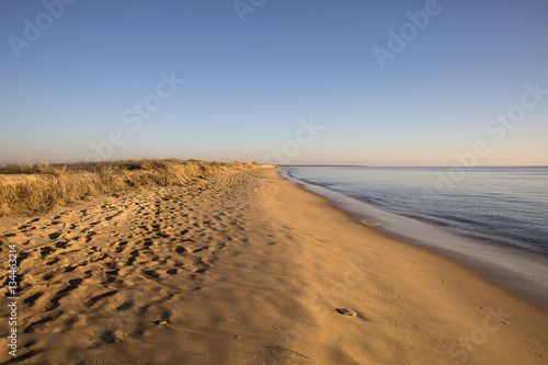 view on a beach at sunset with golden sand an quiet sea