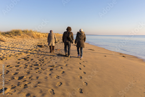 people walking on the beach by romantic winter sunset