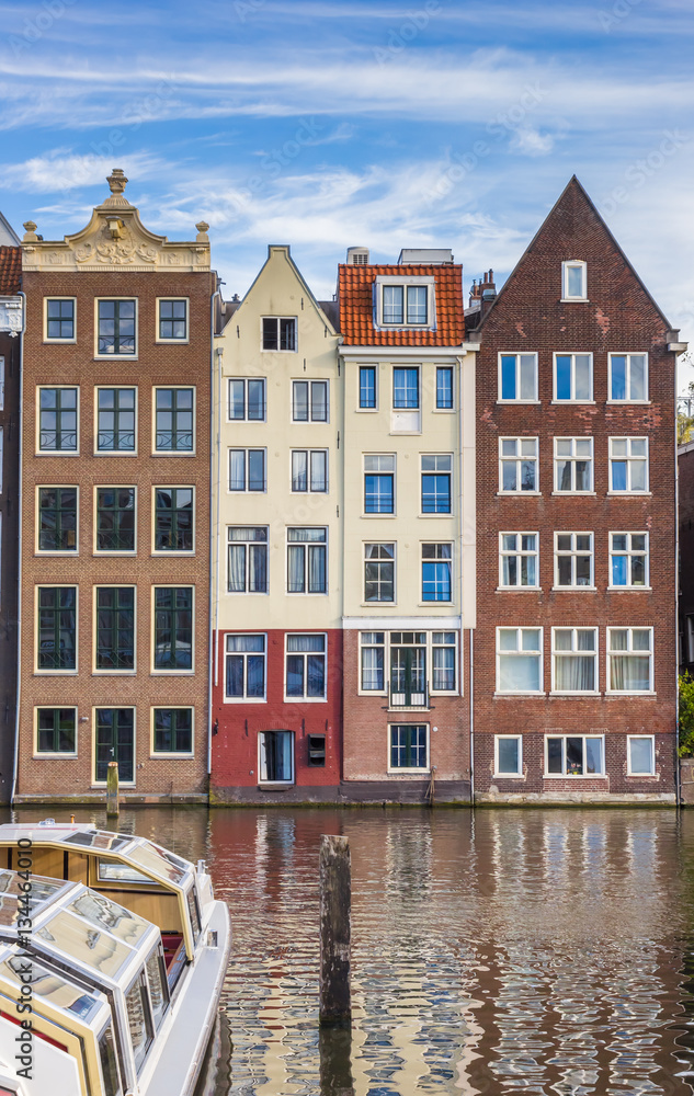 Traditional houses and a cruiseboat at the Damrak in Amsterdam