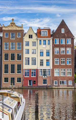 Traditional houses and a cruiseboat at the Damrak in Amsterdam