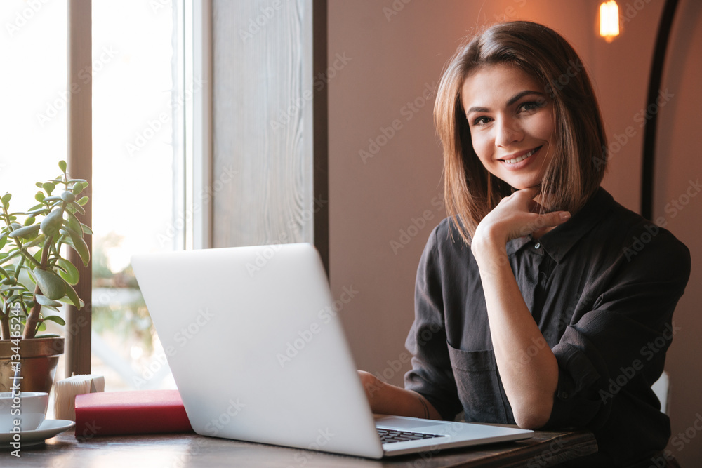 Pretty young woman using laptop computer. Look at camera. Pretty young woman using laptop computer. Look at camera.