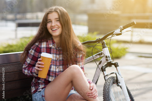 Young woman drinking coffee on a bicycle trip © George Dolgikh