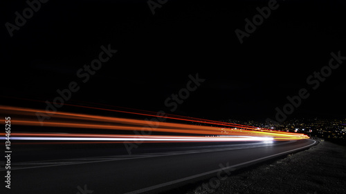Dowhill light trails, cyty light in background
