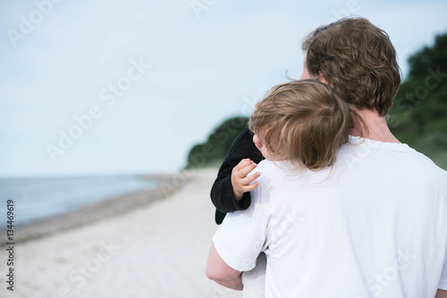 Vater trägt Kind auf dem Arm am Strand photo