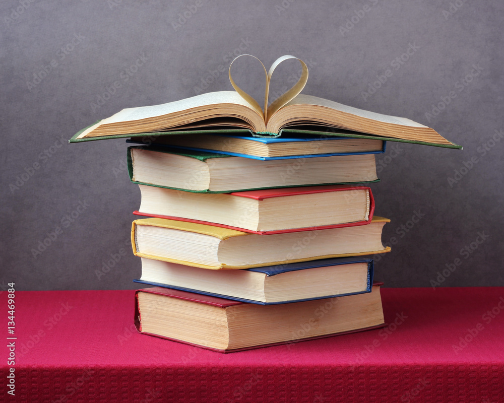 stack of books on the table, an open book on top. StockFoto Adobe Stock