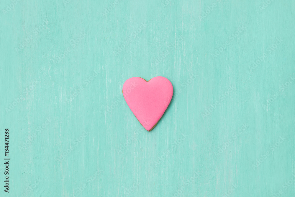 Top view on a little gingerbread cookie in shape of heart on light blue background. Flay layout. Love, Valentines's day concept