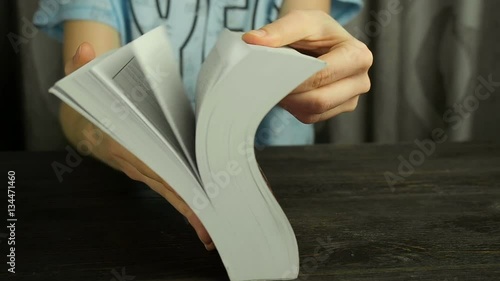 Female hands turning the pages of a book quickly, close up