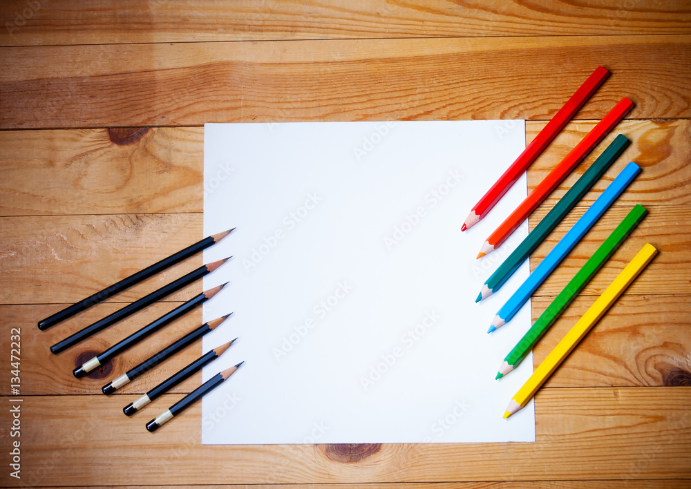 Obraz premium Blank paper and graphite and colorful pencils on the wooden background