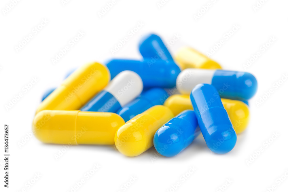 pile of blue, yellow color medical pills on white background pile of blue, yellow color medical pills on white background