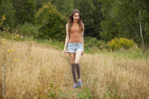 Young beautiful woman walking in a field, summer outdoors