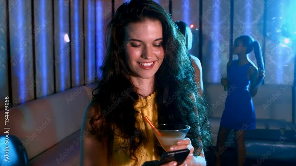 Smiling woman with cocktail drink typing a message in the bar 4K Smiling woman with cocktail drink typing a message in the bar 4K