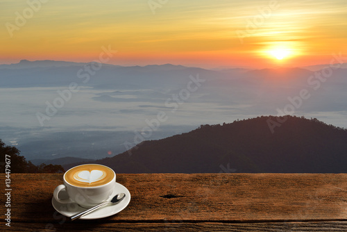 Morning cup of coffee latte with mountain background at sunrise