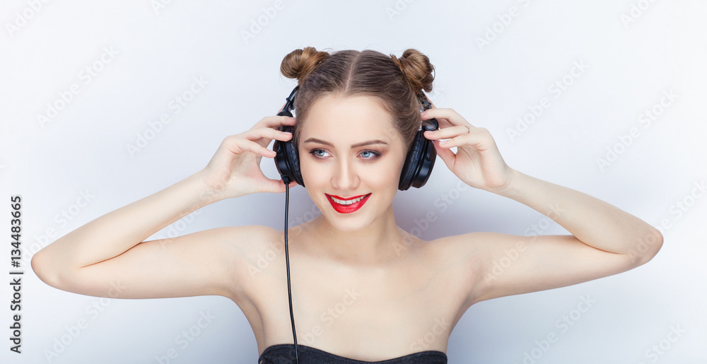 Young pretty woman trendy makeup bright red lips bun hairstyle bare shoulders act the ape with big dj headphones on white studio background Young pretty woman trendy makeup bright red lips bun hairstyle bare shoulders act the ape with big dj headphones on white studio background