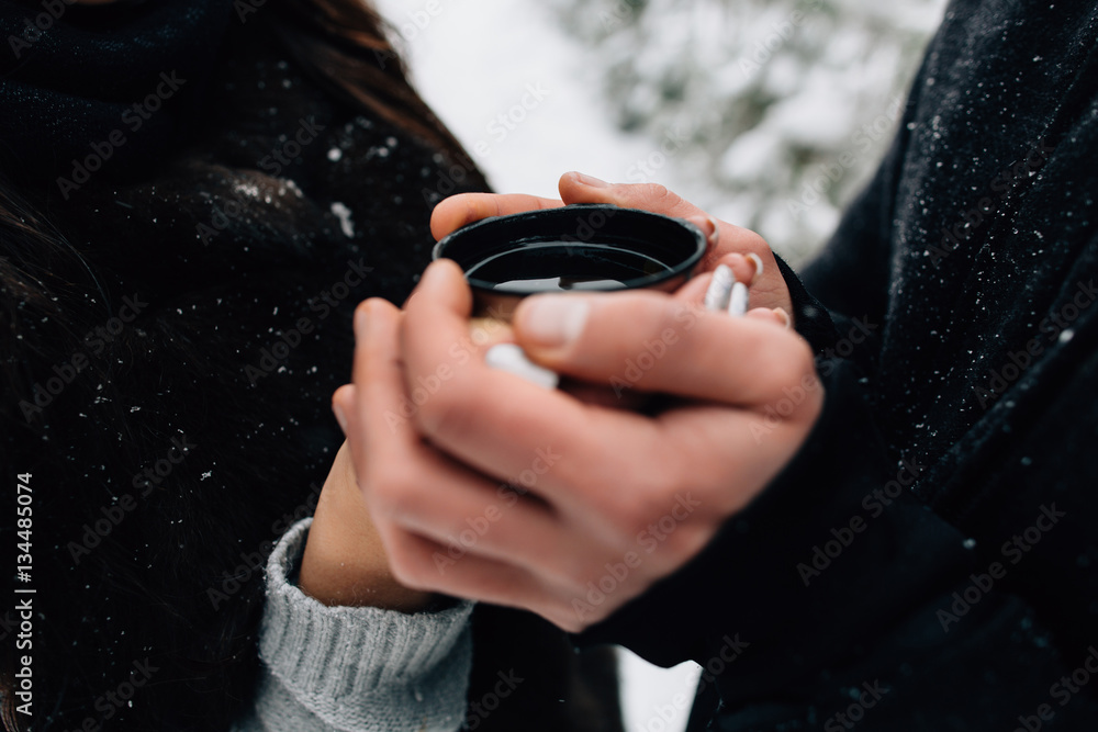 Hands of couple in love holding cup of hot tea in cold winter day Hands of couple in love holding cup of hot tea in cold winter day