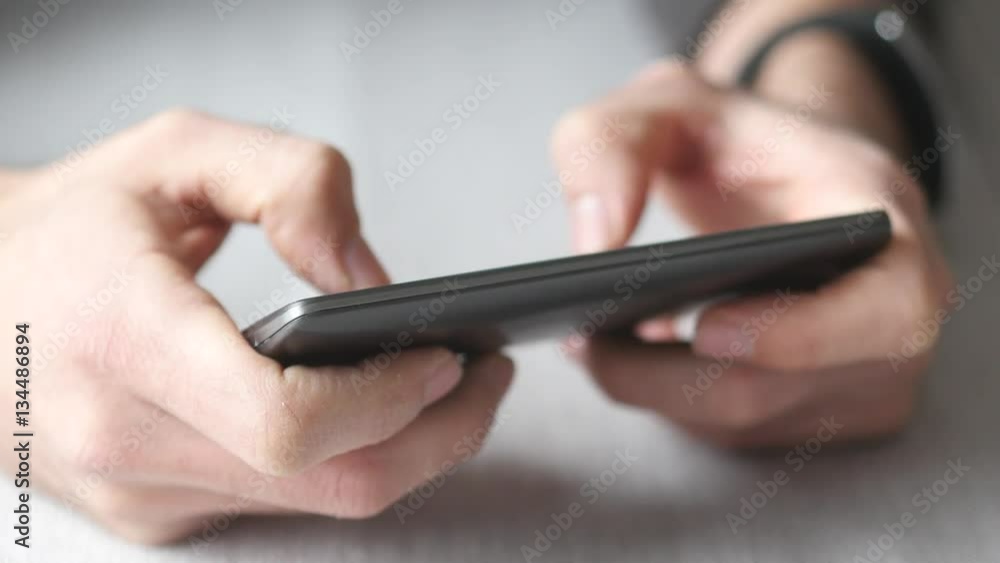 Sitting at a table and using a smartphone device. Closeup shot.