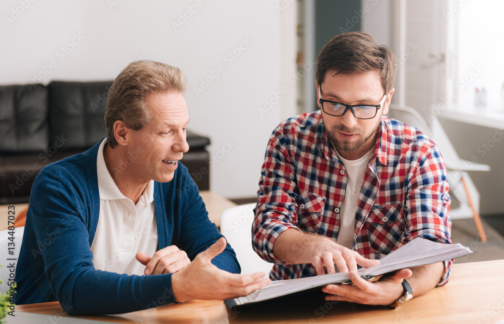 Nice hard working men looking at the folder with documents Nice hard working men looking at the folder with documents