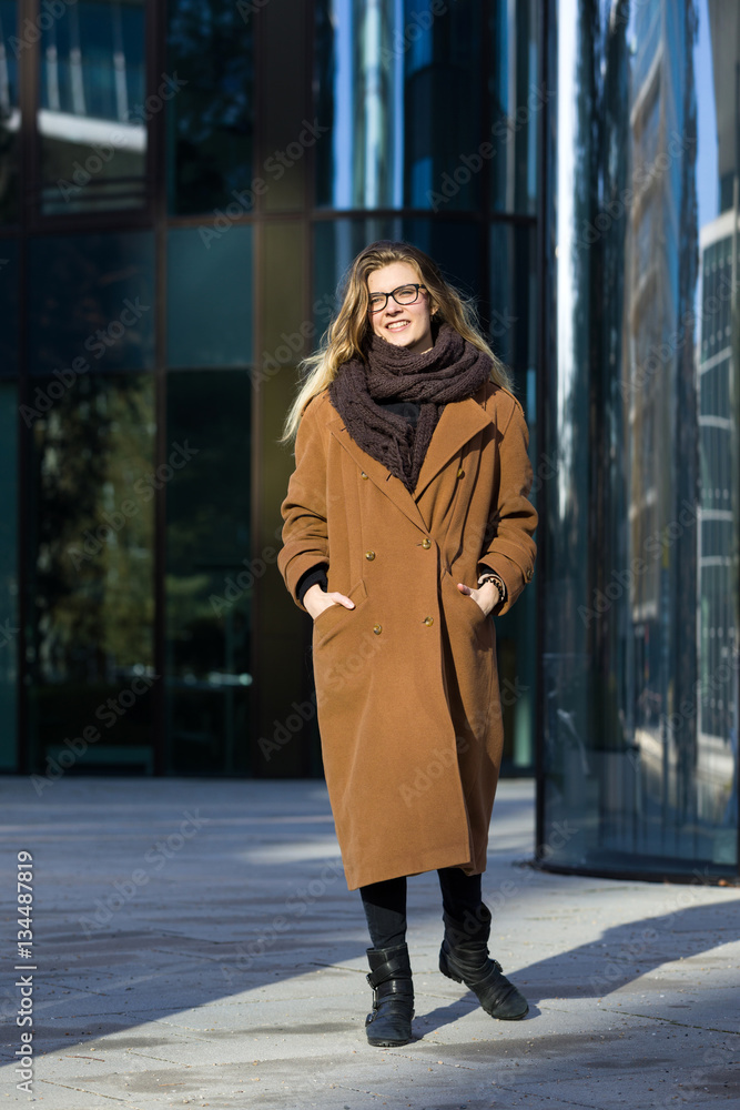 Smiling young woman in winter clothes in front of office buildings