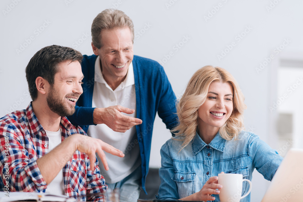 Cheerful nice colleagues looking at the laptop screen Cheerful nice colleagues looking at the laptop screen