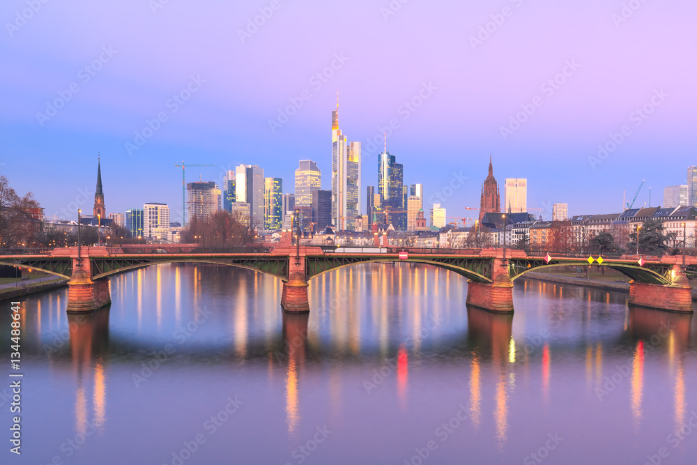 Picturesque view of Frankfurt am Main skyline and Ignatz Bubis Brucke bridge at sunrise with mirror reflections in the river, Germany