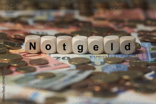 notgeld - Holzwürfel mit Buchstaben im Hintergrund mit Geld, Geldscheine