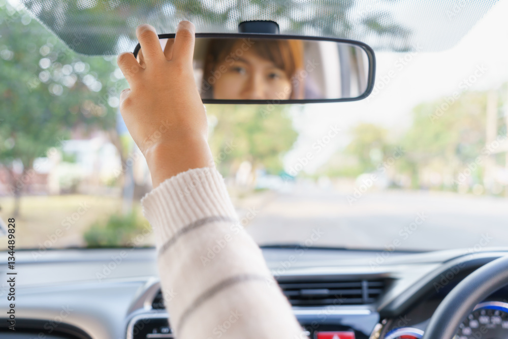 Woman hand adjusting rear view mirror of her car.