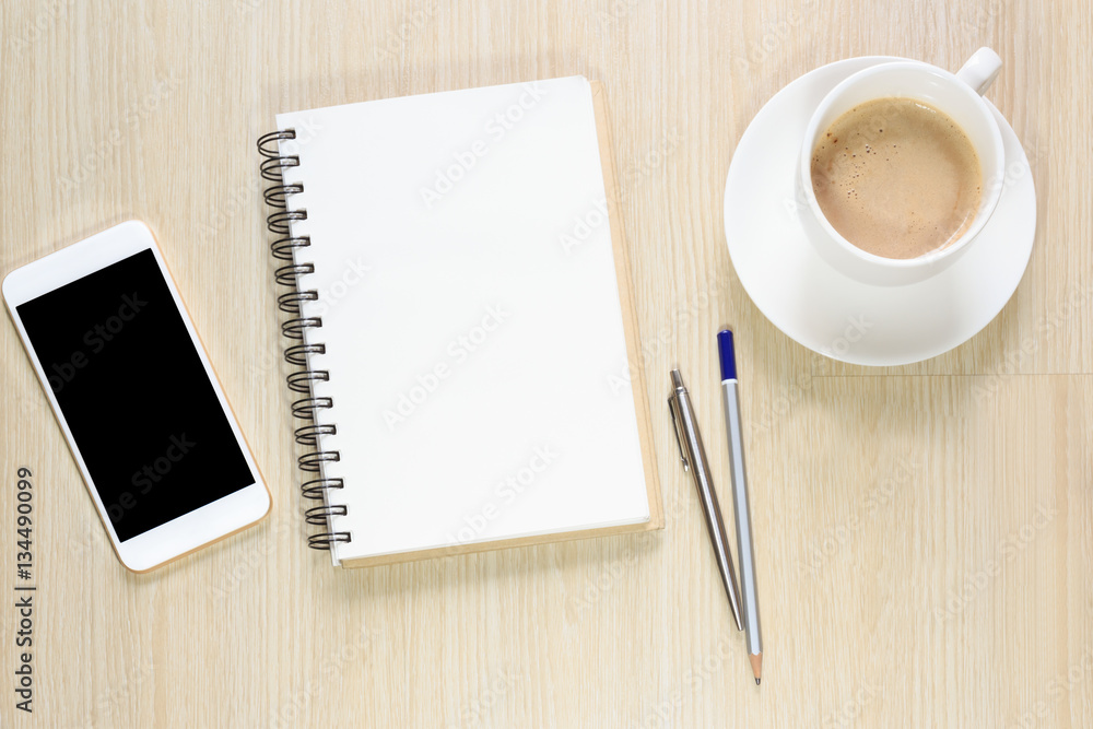 Top view of blank notepad on office desk with smartphone, pen and coffee Top view of blank notepad on office desk with smartphone, pen and coffee