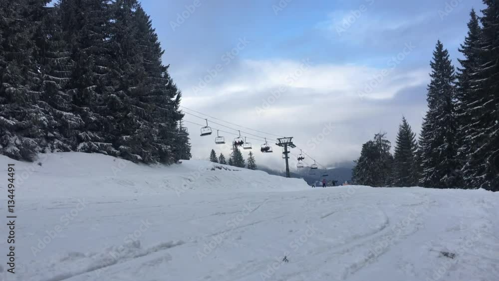 Ski resort scene. Nice sunny day. People ride on the track among the trees. Other sportsmen come to the top on the lift. Ski resort scene. Nice sunny day. People ride on the track among the trees. Other sportsmen come to the top on the lift.