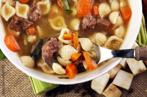 Clear soup with beef and noodles. Broth with carrots, onions var
