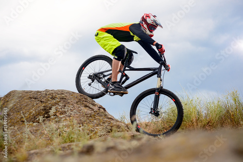 Professional Cyclist Riding the Bike Down Rocky Hill. Extreme Sport Concept. Space for Text.
