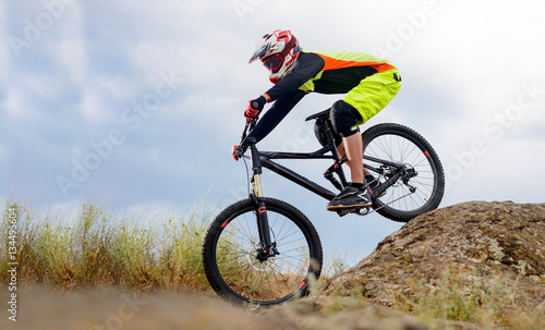 Fototapeta Naklejka Na Ścianę i Meble -  Professional Cyclist Riding the Bike Down Rocky Hill. Extreme Sport Concept. Space for Text.