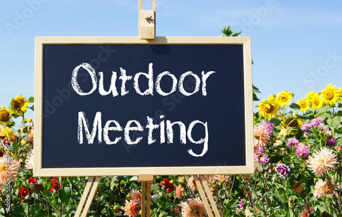 Outdoor Meeting - chalkboard with text in the garden with summer flowers