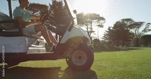 Golfer driving in his golf buggy at golf course