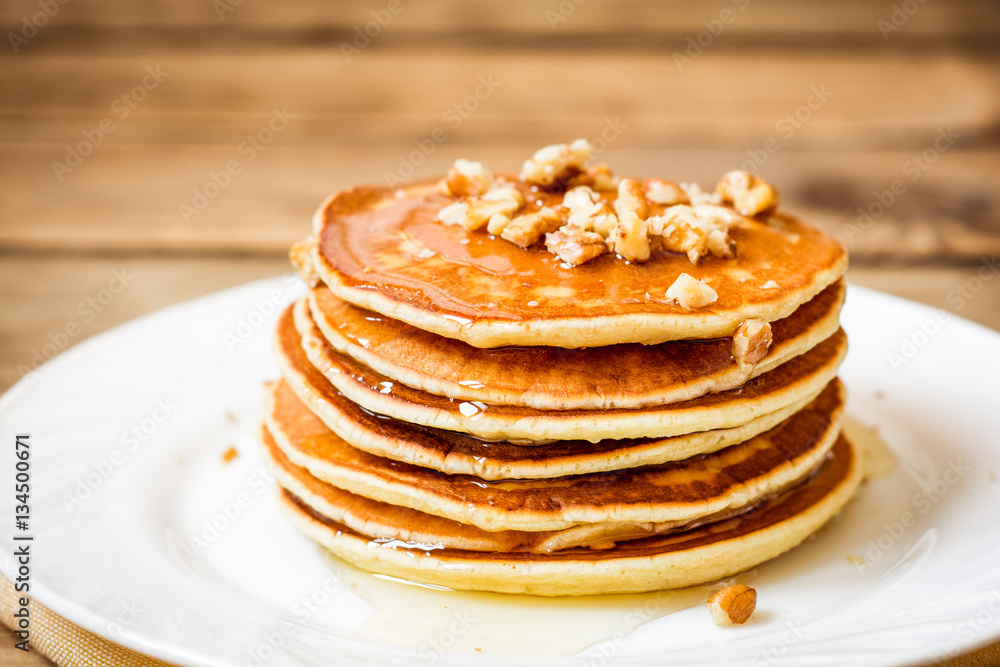 Pancakes with honey and walnuts on rustic wooden background Pancakes with honey and walnuts on rustic wooden background