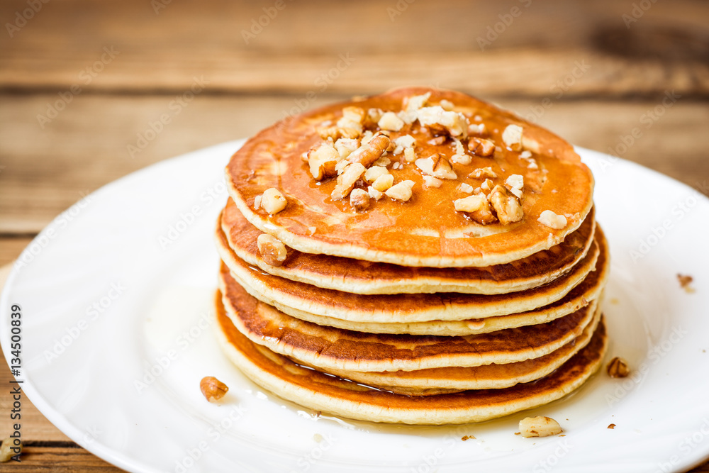 Pancakes with honey and walnuts on rustic wooden background Pancakes with honey and walnuts on rustic wooden background