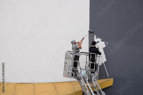 Two worker are paiting exterior of building
