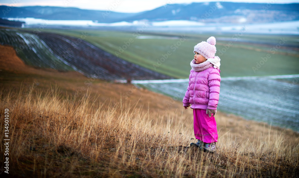Portrait of a little girl alone in the field. Winter time