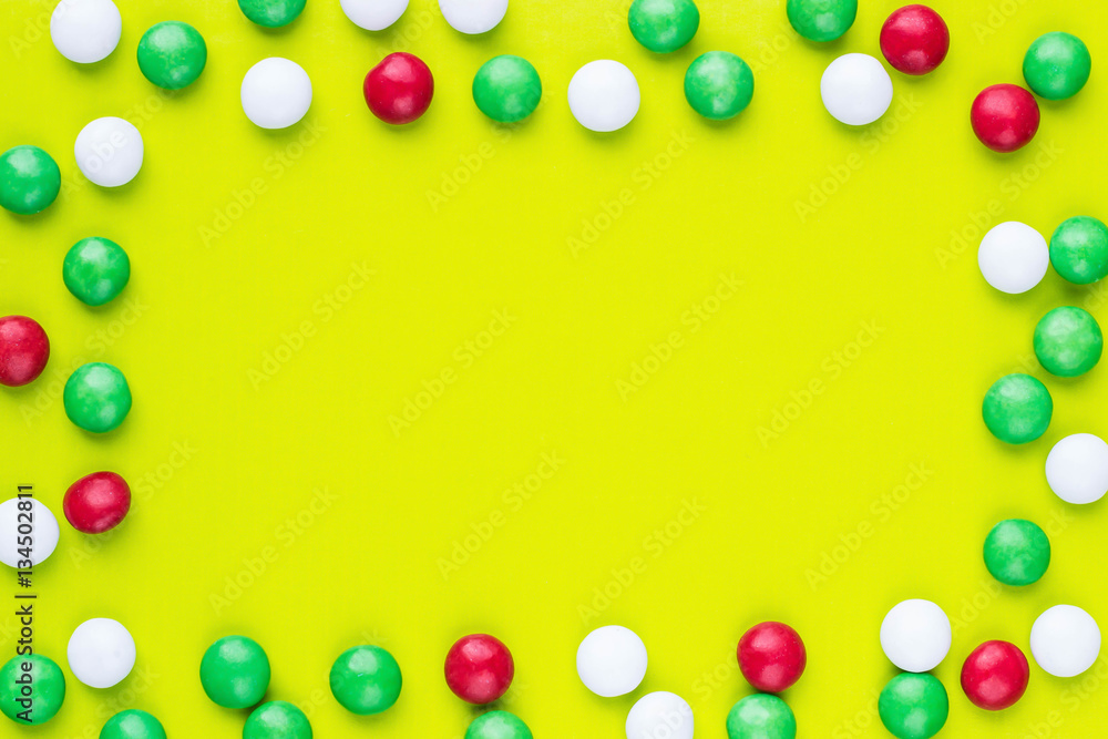 Colored candies in a frame shape on the green background