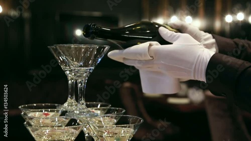 Waiter pours champagne in glass tower of champagne coctail restaurant