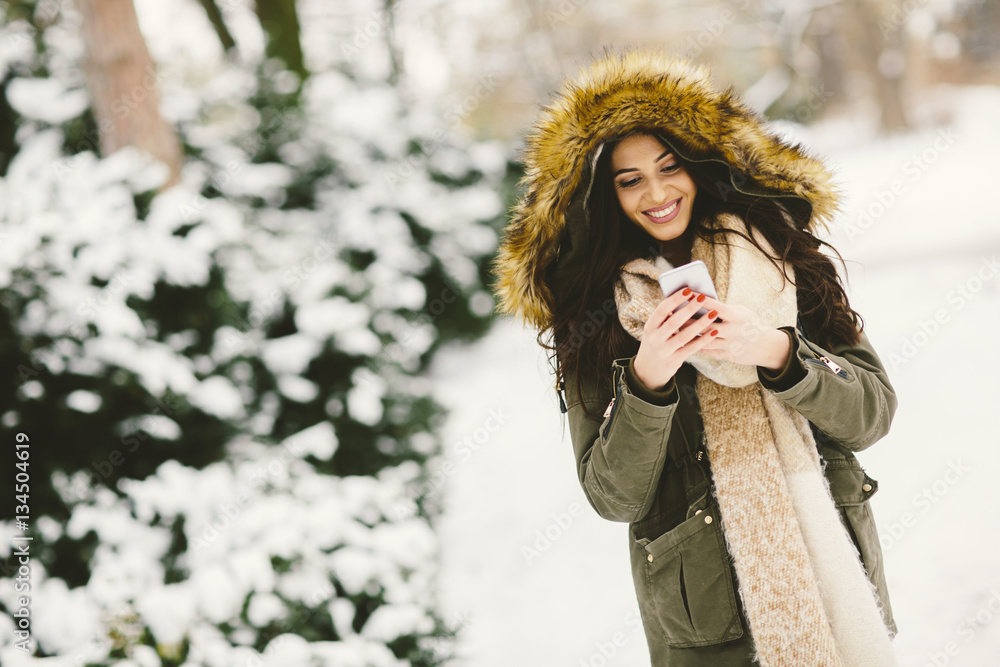 Young woman using a phone in the winter park Young woman using a phone in the winter park
