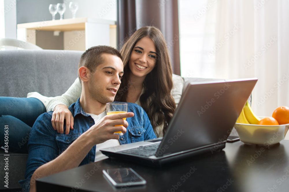 Cheerful couple searching something on laptop at home. Cheerful couple searching something on laptop at home.