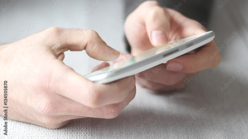 White smartphone being used while sitting at a table. Closeup on the device. White smartphone being used while sitting at a table. Closeup on the device.