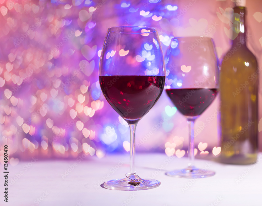Two glasses with wine with hearts shaped bokeh background. St. Valentines Day